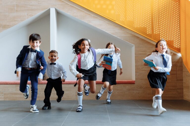 Young students in uniform walking into a private school building.